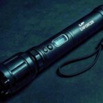 Paralizator z latarką ZAP Enforcer 2 000 000 V na ciemnym tle.