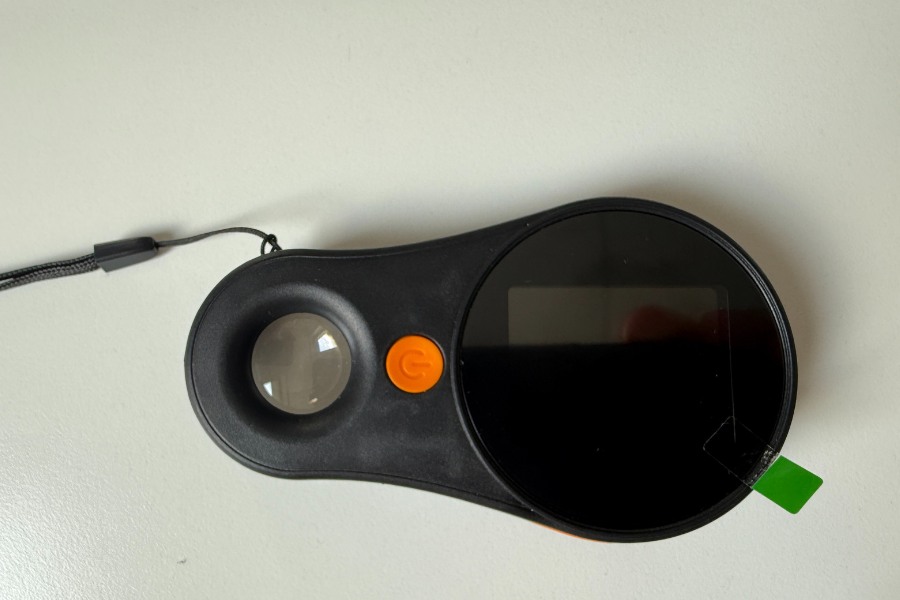 Przednia część lupy cyfrowej Inskam 370, widoczne szkło, pomarańczowy przycisk oraz