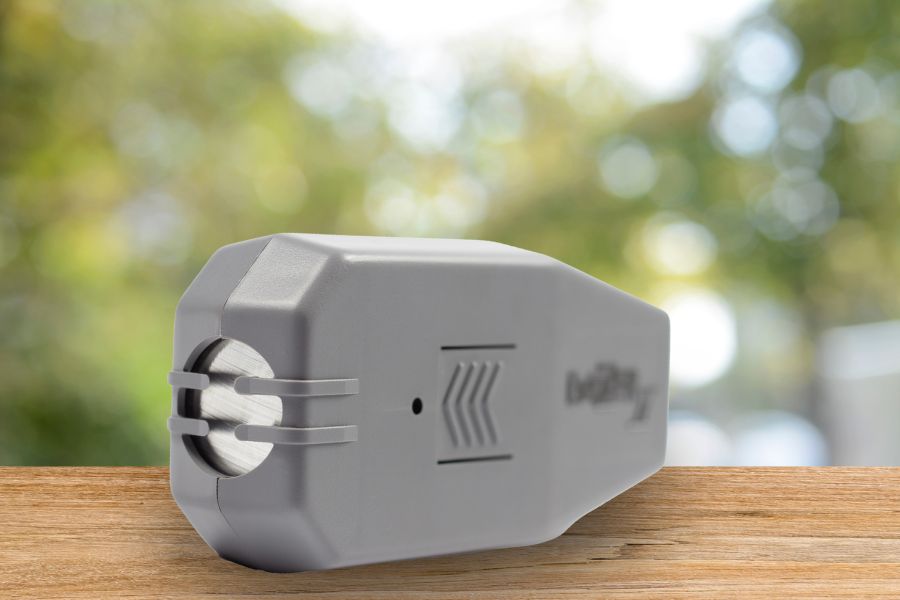 Profesjonalny odstraszacz psów Dazer II na drewnianym stole, w tle zieleń.