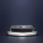 Dyktafon ukryty w pendrive MQ-U310 na szarej podstawce. Tło w ciemnych barwach.