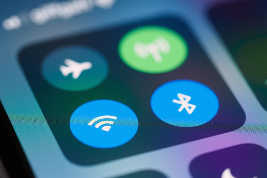 Zbliżenie na ekran smartfona z włączonymi ikonami Wi-Fi, Bluetooth, trybu samolotowego i transmisji danych, symbolizujące łączność bezprzewodową.