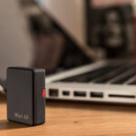 Urządzenie Mini A8 umieszczone na biurku w pobliżu laptopa, pokazujące jego kompaktowy rozmiar i dyskretną konstrukcję.