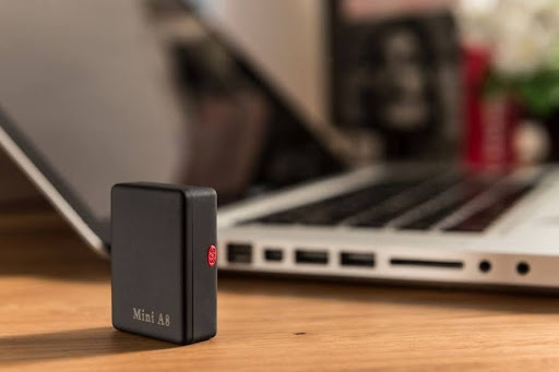 Urządzenie Mini A8 umieszczone na biurku w pobliżu laptopa, pokazujące jego kompaktowy rozmiar i dyskretną konstrukcję.