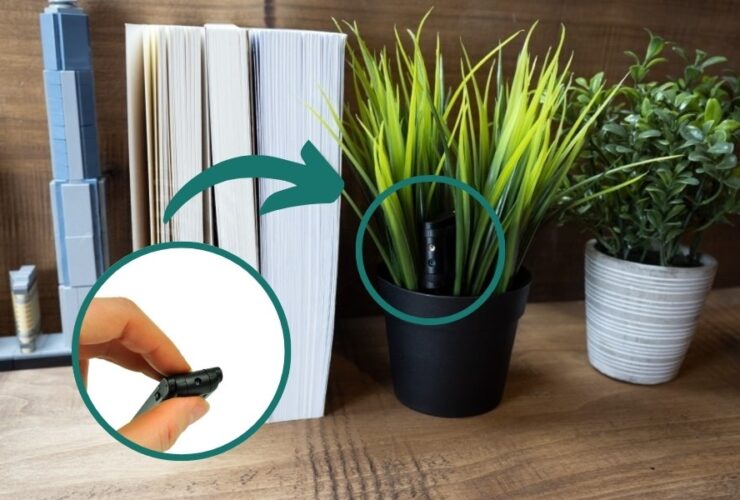 Rośliny w doniczkach i książki stoją na drewnianym blacie, w jednej z roślin widoczna jest ukryta mini kamera. Zbliżenie na sprzęt w małej ilustracji po lewej stronie.