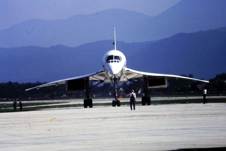 Fotografia przedstawiająca samolot naddźwiękowy kołujący na pasie startowym. W tle widoczny zarys wysokich gór.