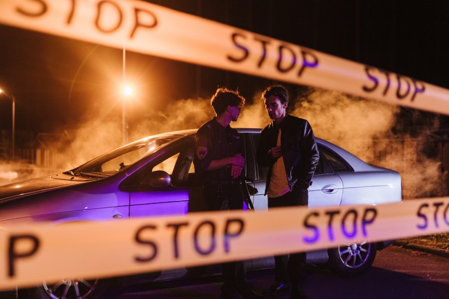 Na zdjęciu widocznych jest dwóch mężczyzn stojących przed autem w nocy.