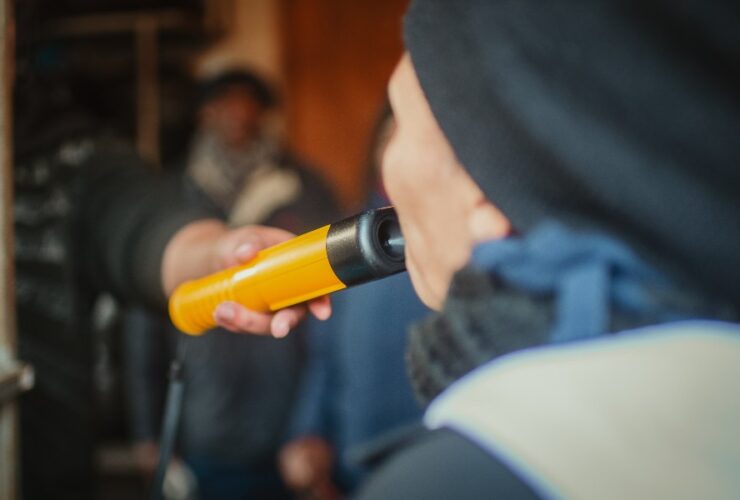 Kobieta podczas policyjnej kontroli dmucha w alkomat, aby sprawdzić poziom alkoholu w wydychanym powietrzu.