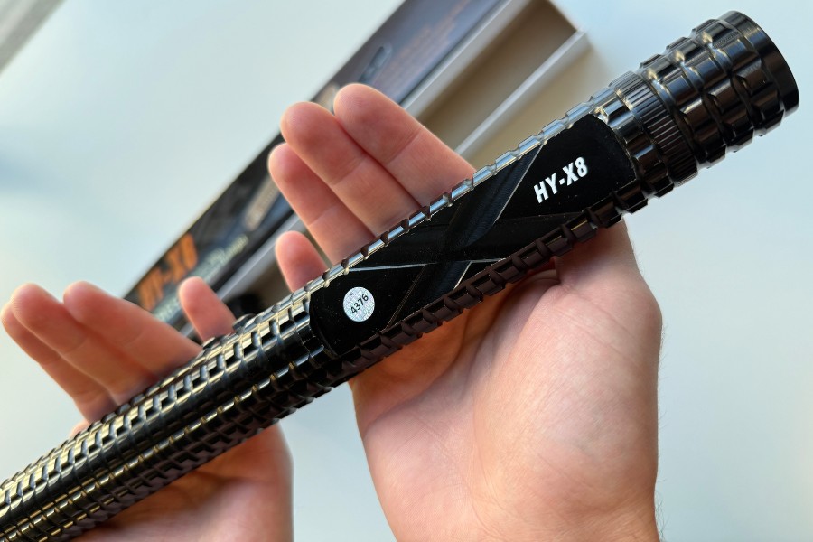 Paralizator Paralyseur X8 w dłoniach, widoczne oznaczenie modelu i metalowa obudowa.