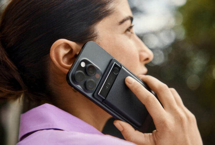 Kobieta trzyma smartfon z dyktafonem PLAUD Note Pro przy uchu podczas rozmowy na zewnątrz