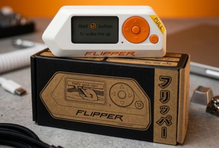 Urządzenie Flipper Zero z pomarańczowymi przyciskami leży na pudełku.