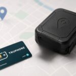 Po prawej stronie widoczny jest czarny lokalizator GPS, a obok niego znajduje się karta SIM. W tle widoczna jest mapa.